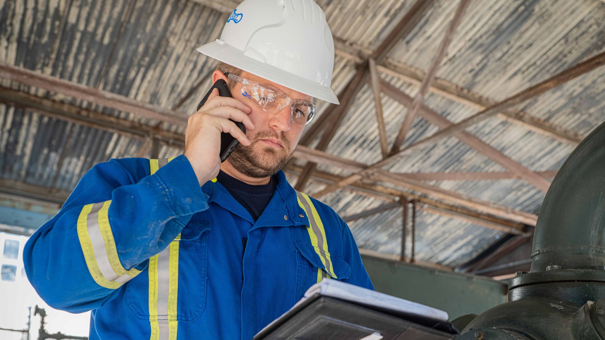 Ariel Technician at a compression station holding a clipboard and placing a phone call