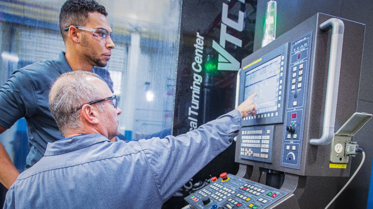 Two Ariel employees work on a CNC machine