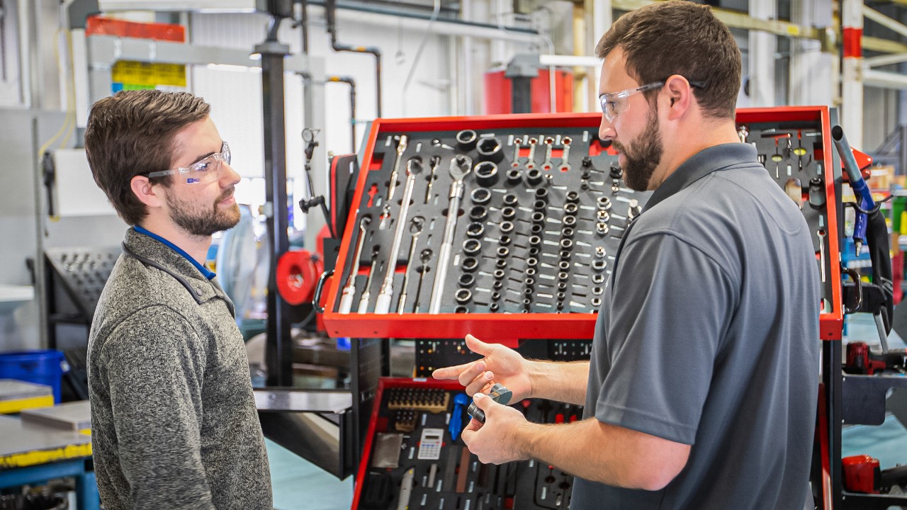 A Supervisor instructs his Co-op about tools in the manufacturing facility