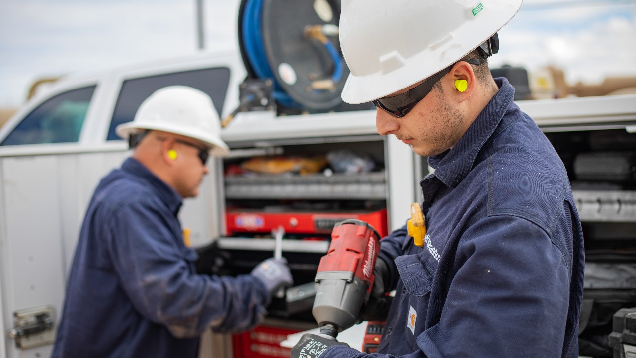 Two mechanics working by a truck at the Sandero compressor station