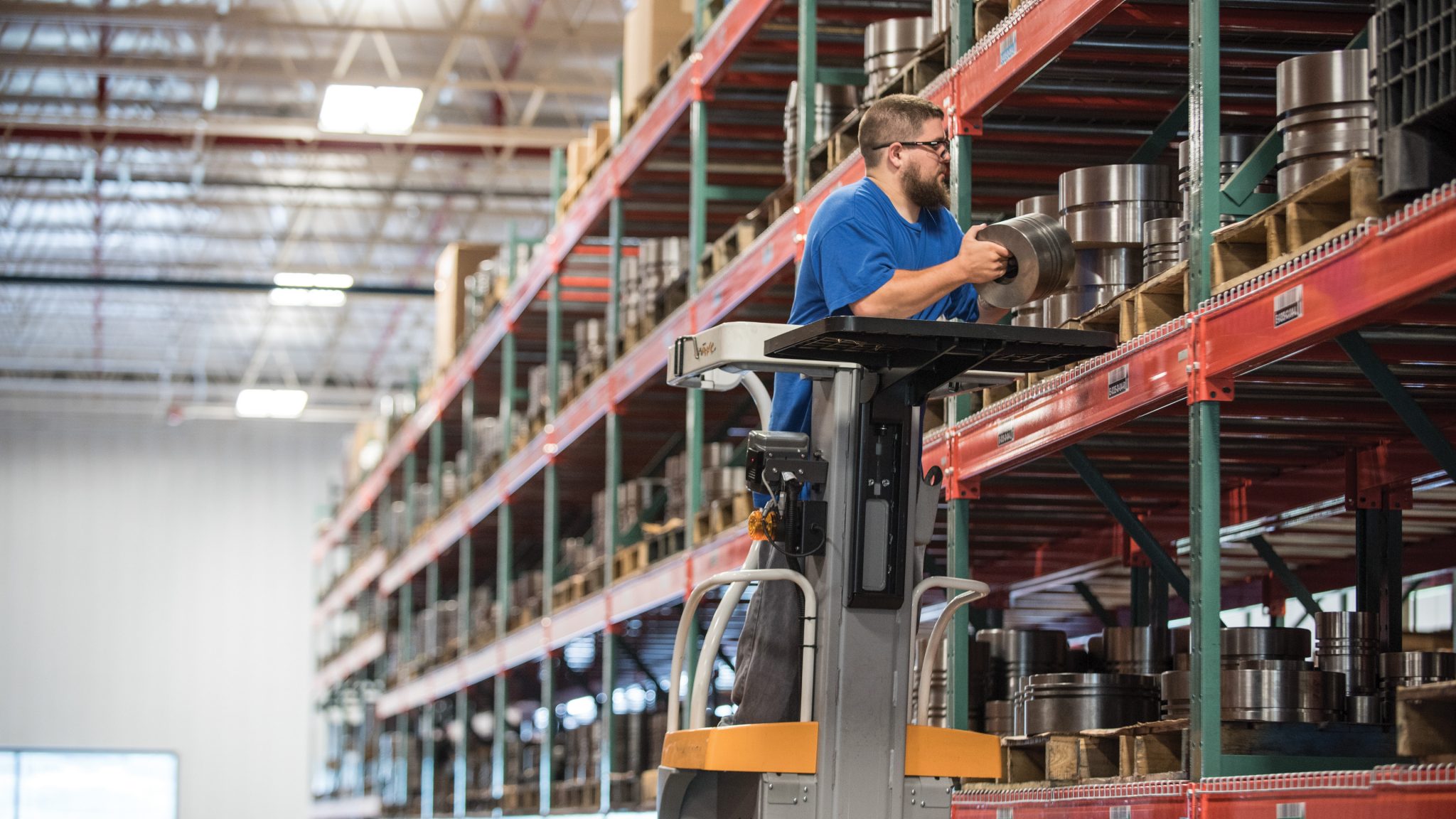 An Ariel employee on personal industrial transport removing a piston head from a rack of parts