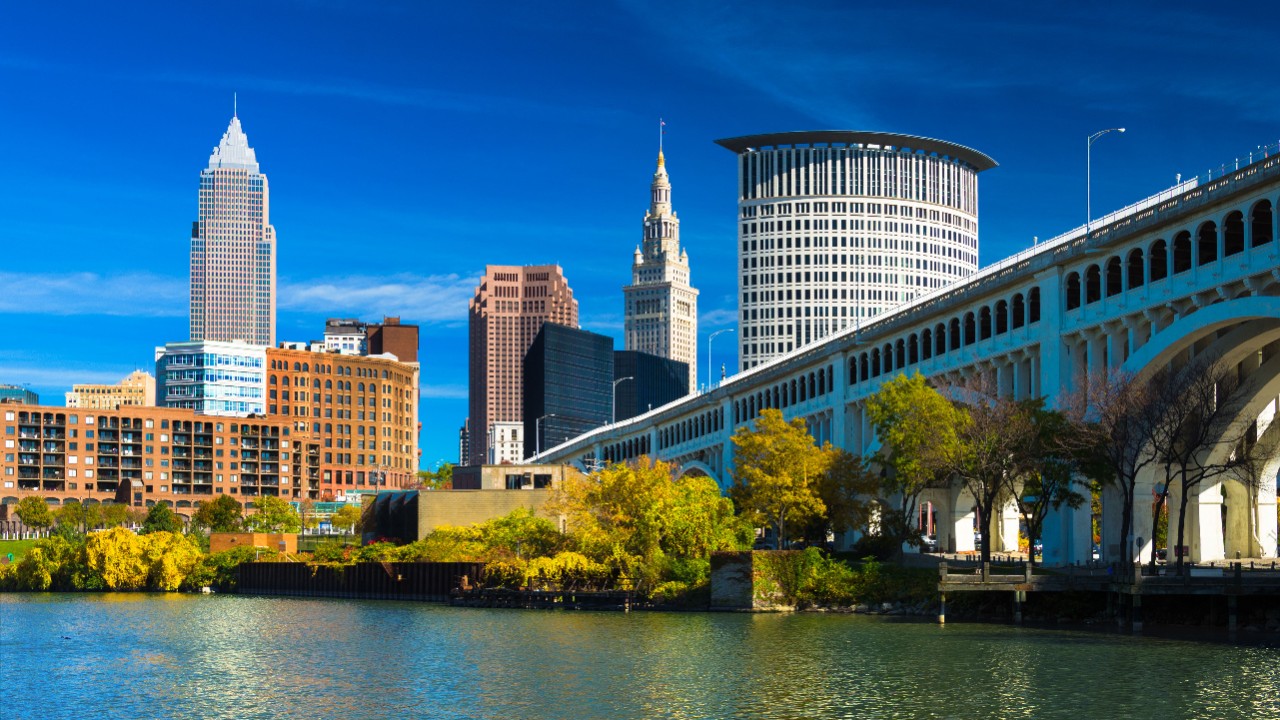 Downtown Cleveland skyline (featuring Key Tower) with the Cuyahoga River, Detroit-Superior Bridge, Autumn colored trees, and a deep blue sky with wispy clouds.  Wide Angle.