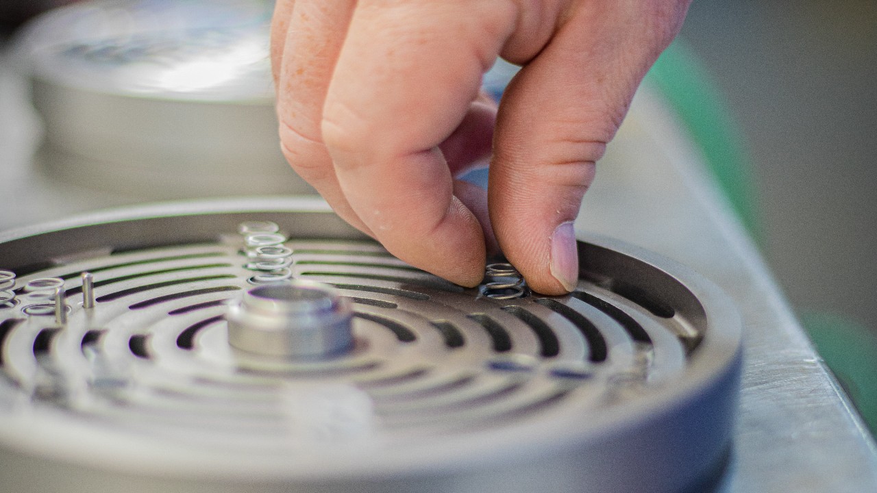 Detail of a hand placing a spring inside of a disassembled CP/CPs valve