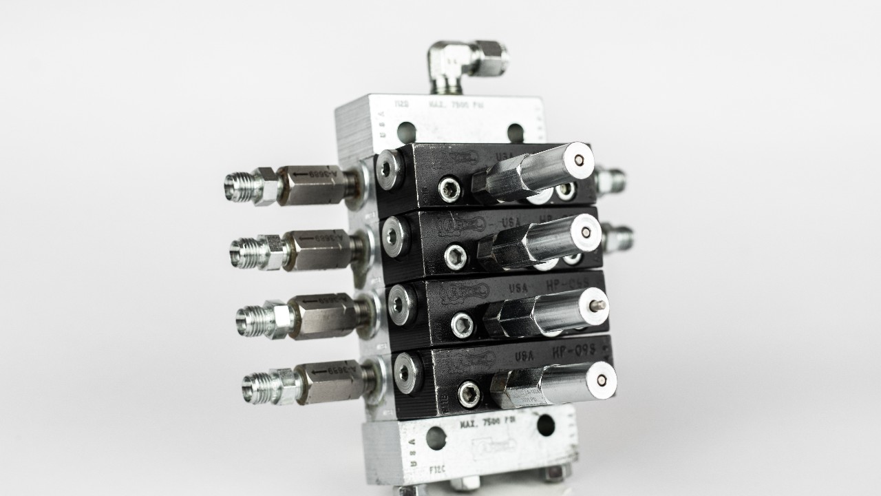 An Ariel Divider block with pin indicators and discharge check valve threads on a white background