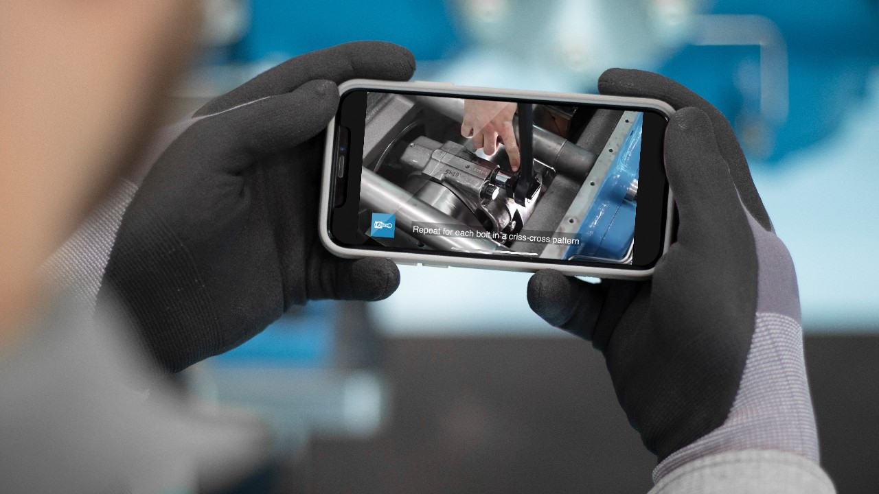 Gloved hands holding a cell phone playing a training video