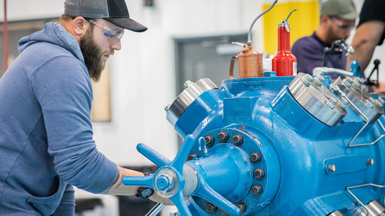 Mechanic with a torque wrench working on a compressor in a training lab